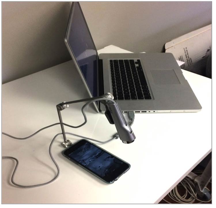 Mobile usability testing set up — a laptop and a camera above a mobile phone on a desk