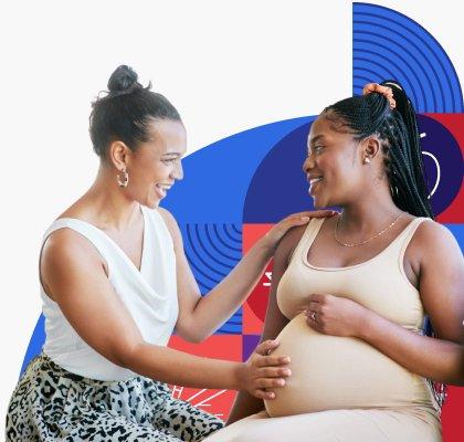 Una mujer de raza negra toca la panza de una mujer embarazada, también de raza negra.
