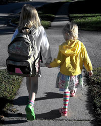 2 girls walking on a sidewalk