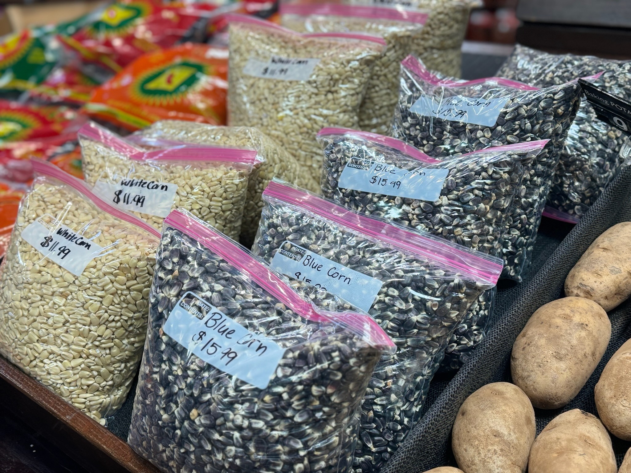 Plastic bags filled with white corn and blue corn, which are traditional Indigenous foods.