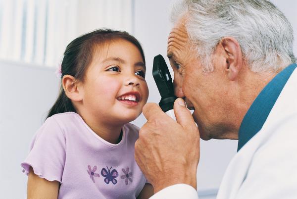 Health care provider looking at young girl's eye
