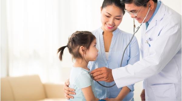 Health care provider using a stethoscope on a young girl while her mother watches