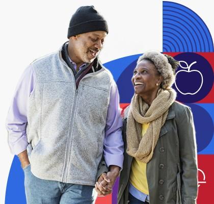 Dos adultos mayores de raza negra, un hombre y una mujer, caminan y sonríen tomados de la mano.
