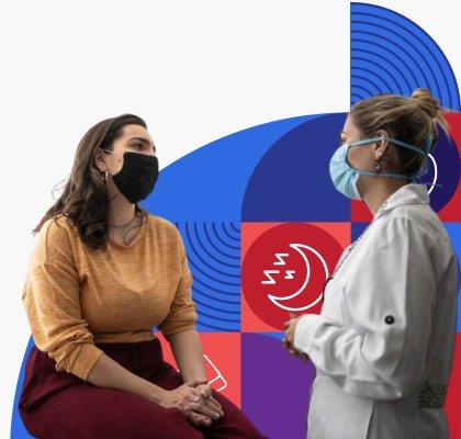 A woman wearing a face mask sits and talks with her healthcare provider.