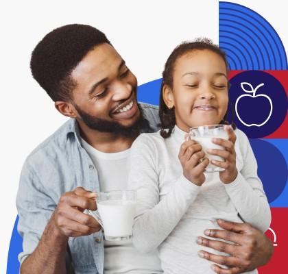 Un padre de raza negra y su hija beben juntos unos vasos de leche.
