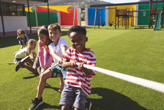 Five children play tug-of war outdoors.