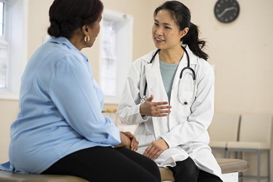 A woman and health care provider sit facing each other and talk.
