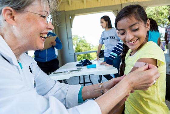 A health care provider puts a bandage on a child's arm.