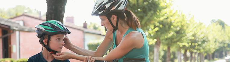 A woman and son pause during their bike ride so she can adjust his helmet.