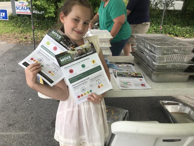 A young community member holds flyers at a Move Your Way event in Southern West Virginia.